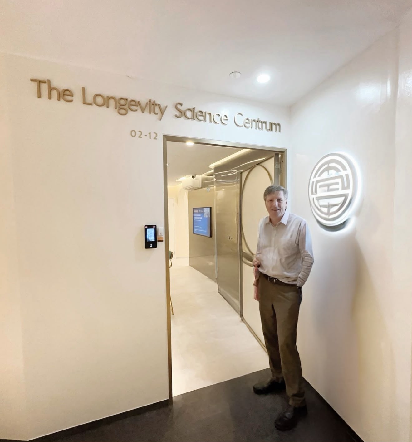 A guest standing at The Longevity Science Centrum's entrance beneath the clinic's name in gold lettering.