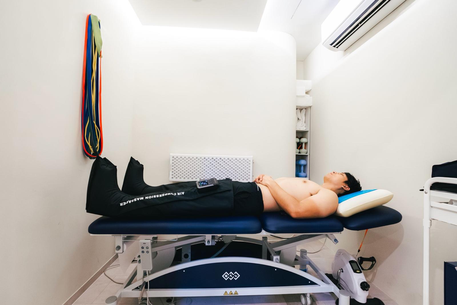 A client resting on a treatment couch wearing air compression massage boots at The Longevity Science Centrum.