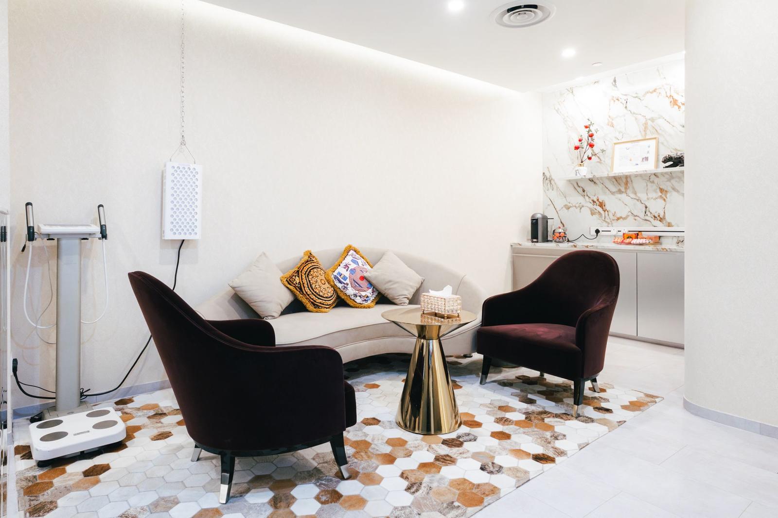 The consultation lounge at The Longevity Science Centrum, with velvet armchairs, a curved sofa and a body composition analyser.