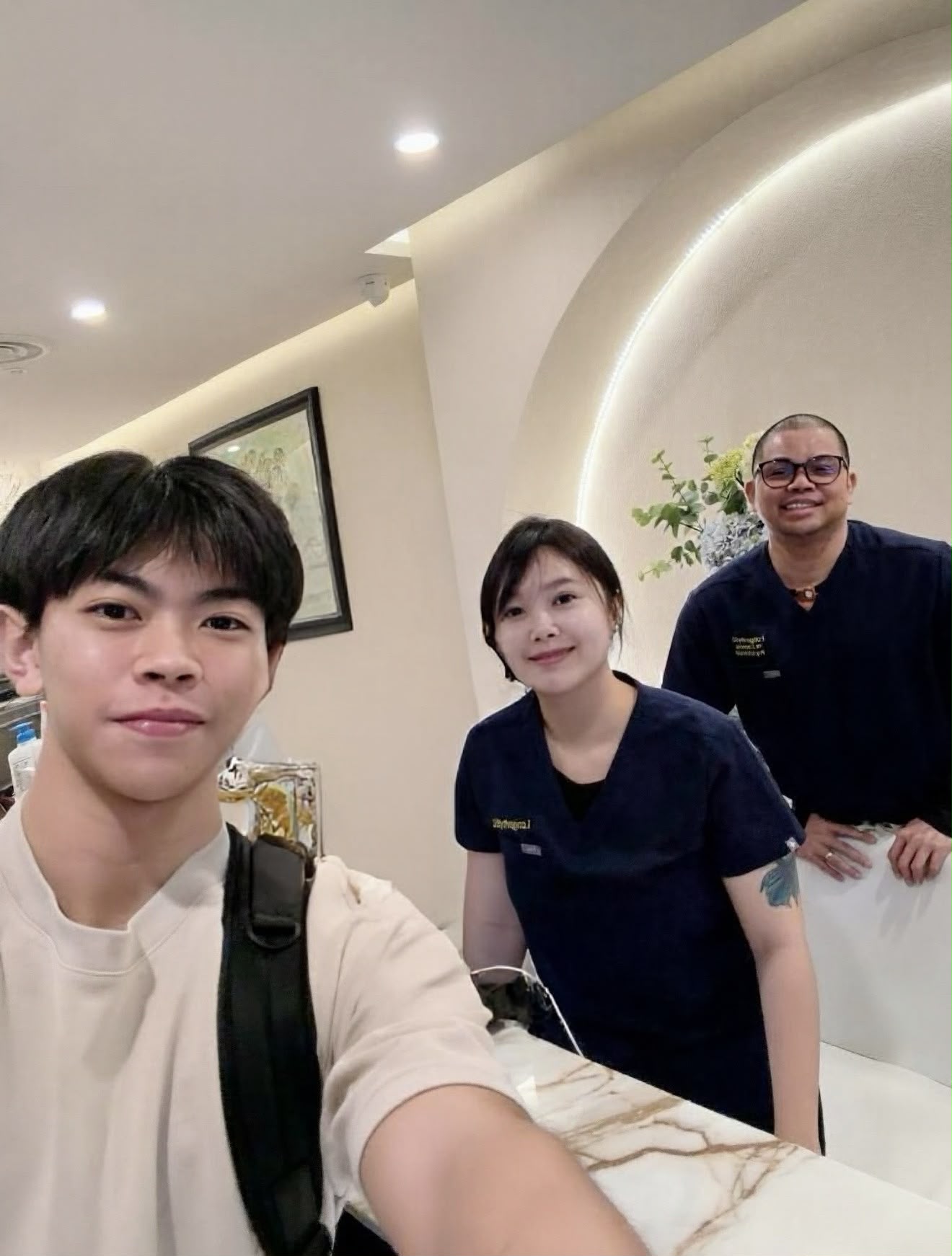 A guest taking a selfie with two team members at The Longevity Science Centrum's reception desk.